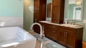 Modern bathroom featuring a freestanding white bathtub, elegant faucet, wooden cabinetry, and a marble counter-top, showcasing Apple Wood Construction's bathroom remodeling expertise.