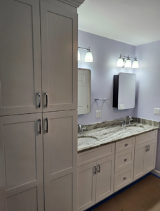 Bathroom remodel in Londonderry, NH featuring custom storage cabinetry, double sink vanity, granite countertops, and modern lighting by Apple Wood Construction.